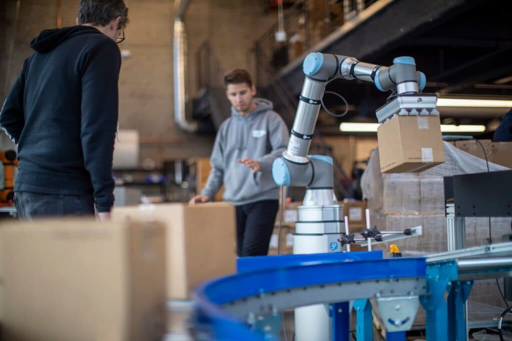 Industrial robot arm palletising boxes inside a guarded cell